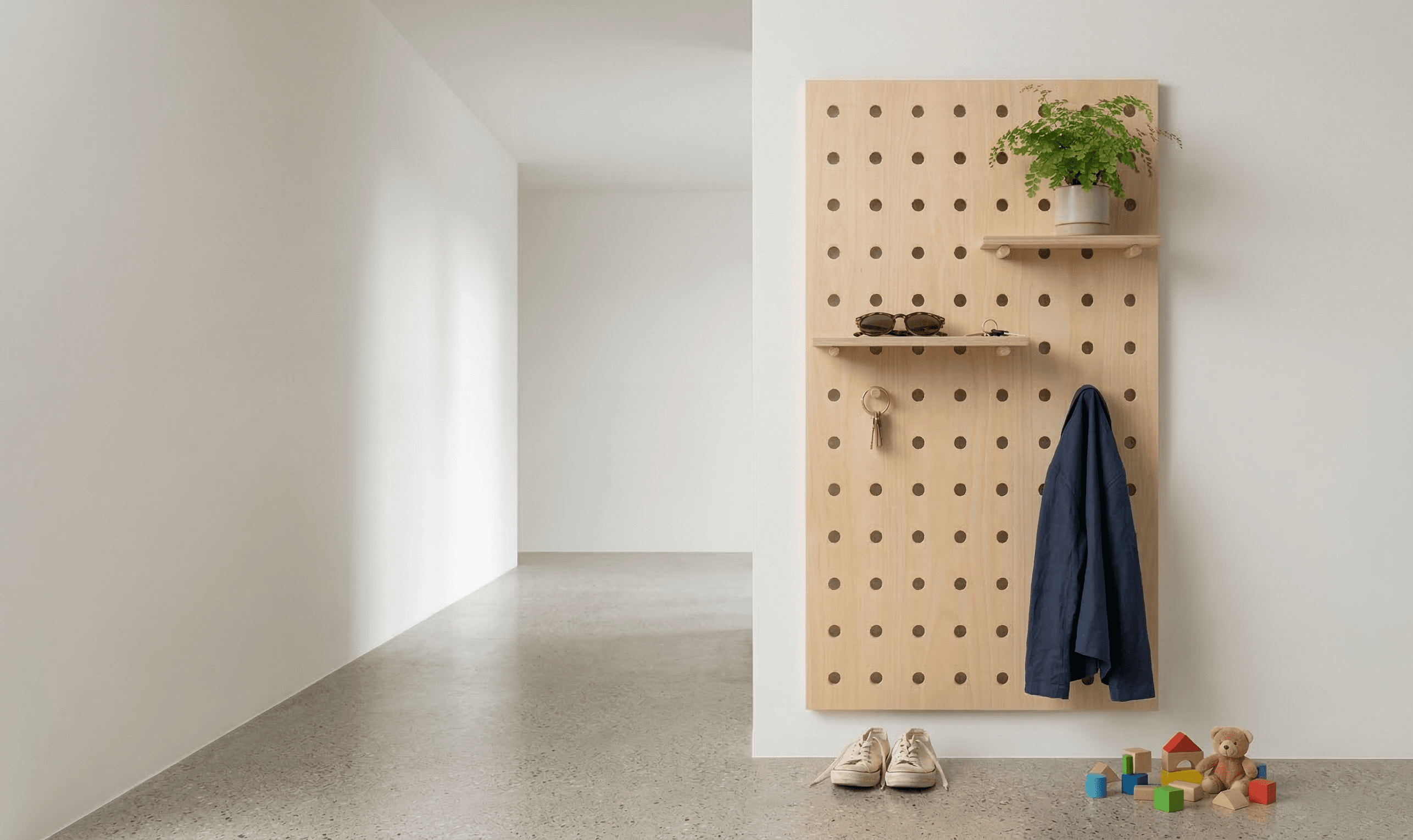 Plywood pegboard in a modern entryway with hooks and a leather bag